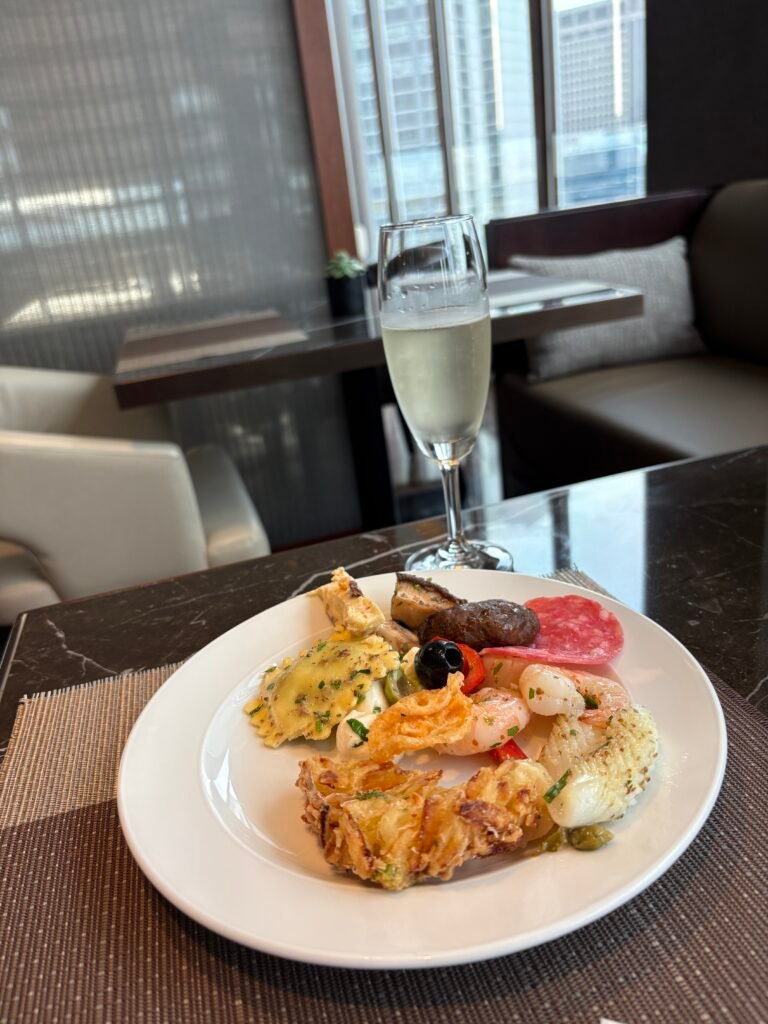 Plate of hot dishes and snacks with a glass of sparkling wine in the executive lounge