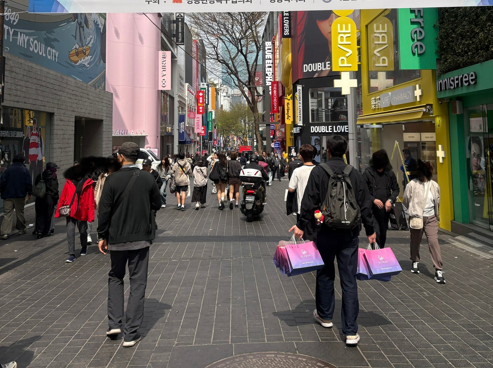 Busy shopping street in Myeongdong, Seoul, with pedestrians, shops and multilingual signs